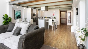 A modern living room with a grey sofa, a dining area with a white table, and a kitchen with stainless steel appliances. - City Stay • 3 Ensuites • SunTerrace • Free Parking | Pass the Keys (Nottingham)