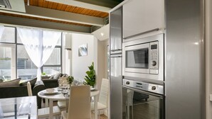 A modern kitchen with a built-in microwave and oven, a dining area with a table and chairs, and a large window with curtains. - City Stay • 3 Ensuites • SunTerrace • Free Parking | Pass the Keys (Nottingham)