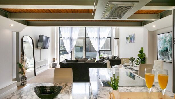 A modern kitchen with marble countertops, a dining area with a table set for two, and a cozy living space with a sofa. - City Stay • 3 Ensuites • SunTerrace • Free Parking | Pass the Keys (Nottingham)