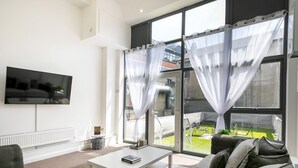 A modern living room with a flat-screen TV, a white coffee table, and grey sofas. - City Stay • 3 Ensuites • SunTerrace • Free Parking | Pass the Keys (Nottingham)