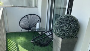A balcony with artificial grass, two black wire-framed chairs, a small table, and a potted plant. - Charming apartment in La Baule, close to shops and beach. (La Baule-Escoublac)