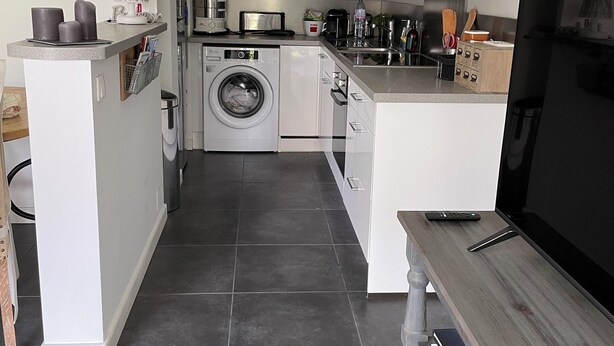 A compact kitchen with a washing machine, a microwave, and a coffee maker. - Charming apartment in La Baule, close to shops and beach. (La Baule-Escoublac)