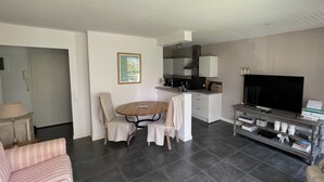 A modern living room with a dining area, a kitchen, and a TV. - Charming apartment in La Baule, close to shops and beach. (La Baule-Escoublac)