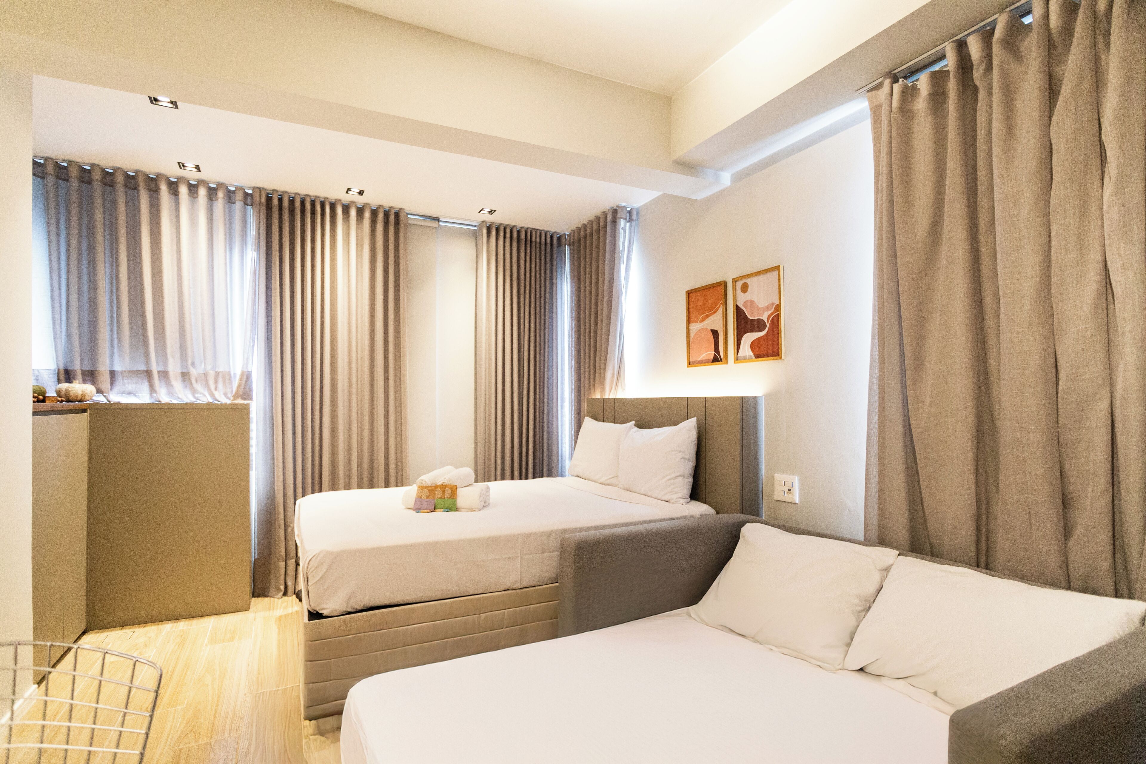 A hotel room with two beds, a desk, and a chair.