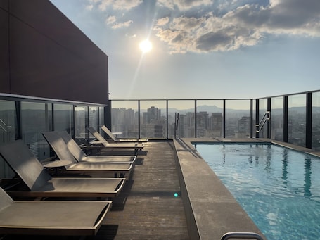Una piscina al aire libre, sombrillas, sillones reclinables de piscina