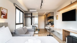 Ein modernes Hotelzimmer mit einem großen Bett, einer Couch, einem Essbereich und einem Fernseher.