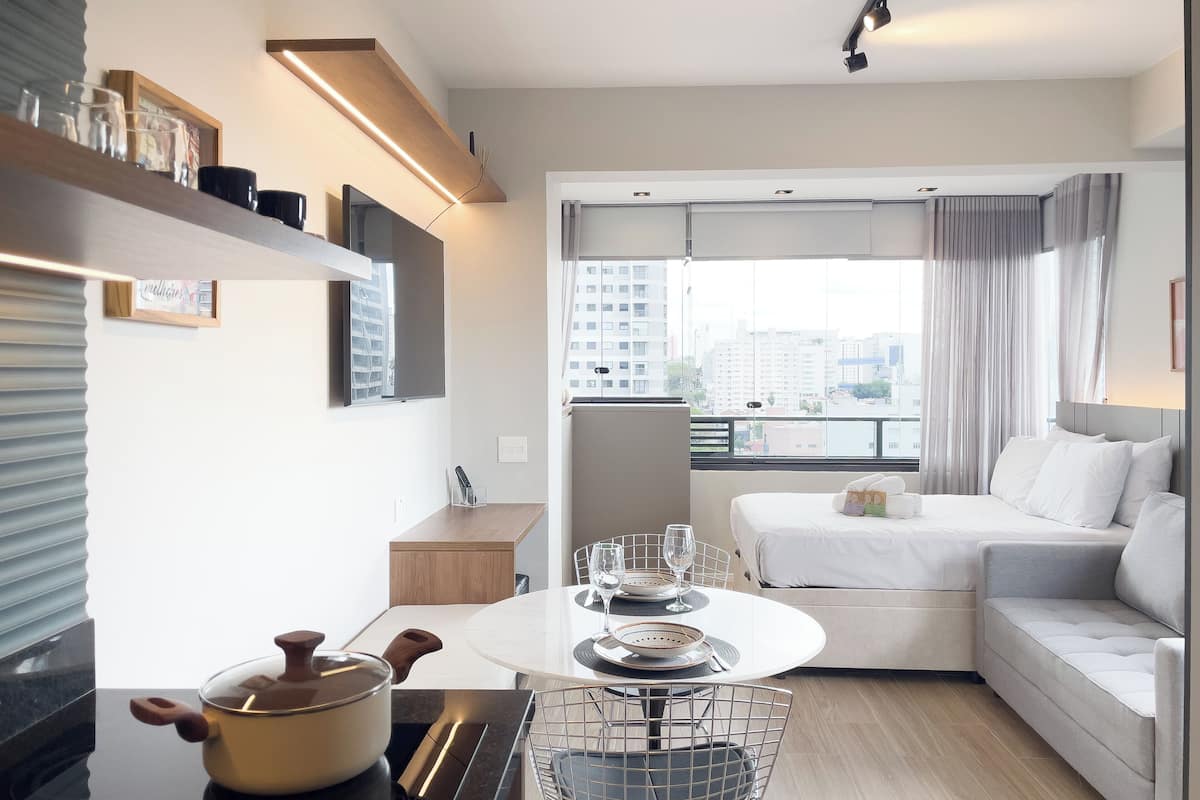 A modern, compact living space with a kitchenette, dining area, and a sofa bed.