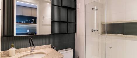 A modern bathroom with a sink, toilet, and glass shower enclosure.