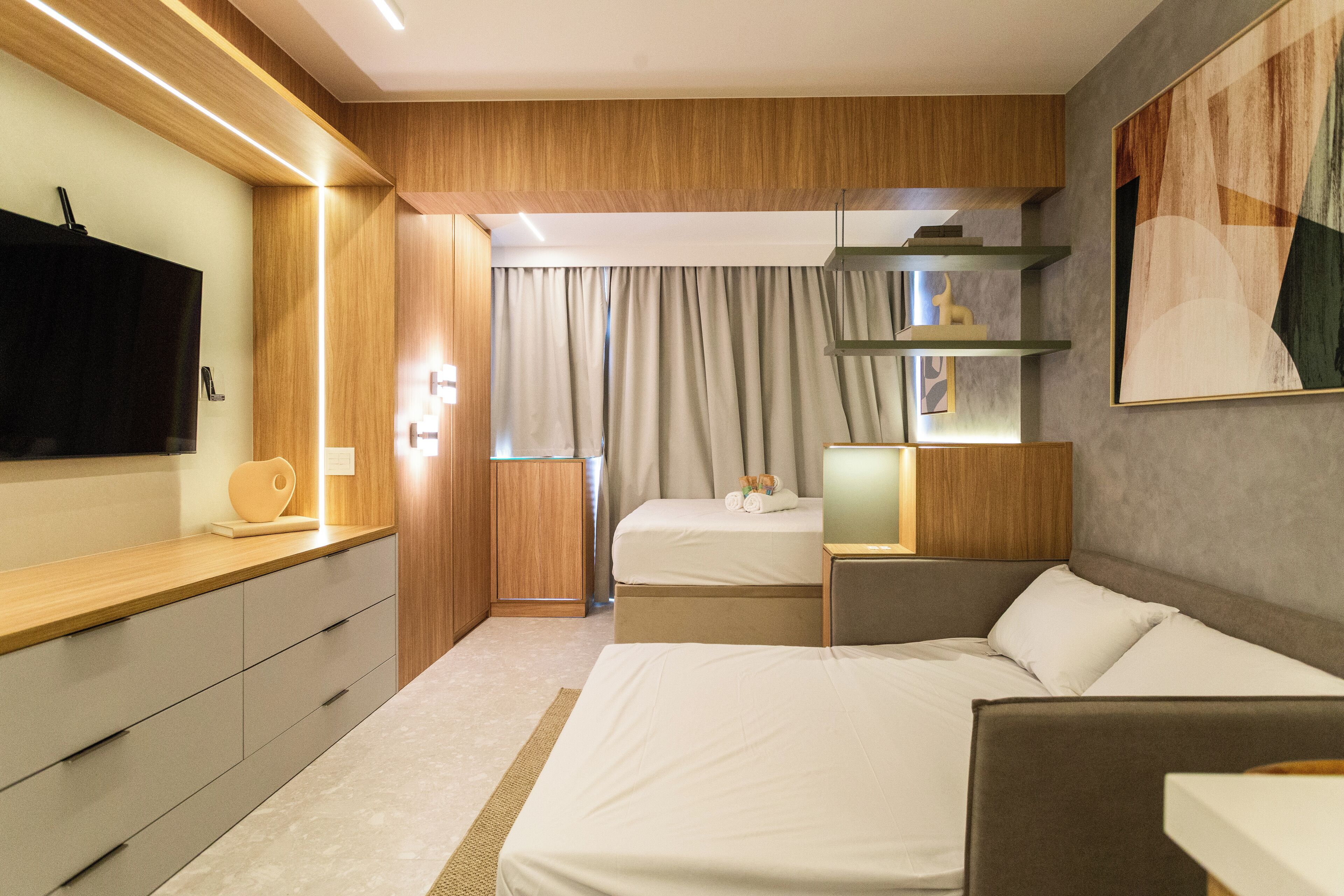 A modern hotel room with a large bed, a desk, a TV, and a painting on the wall.