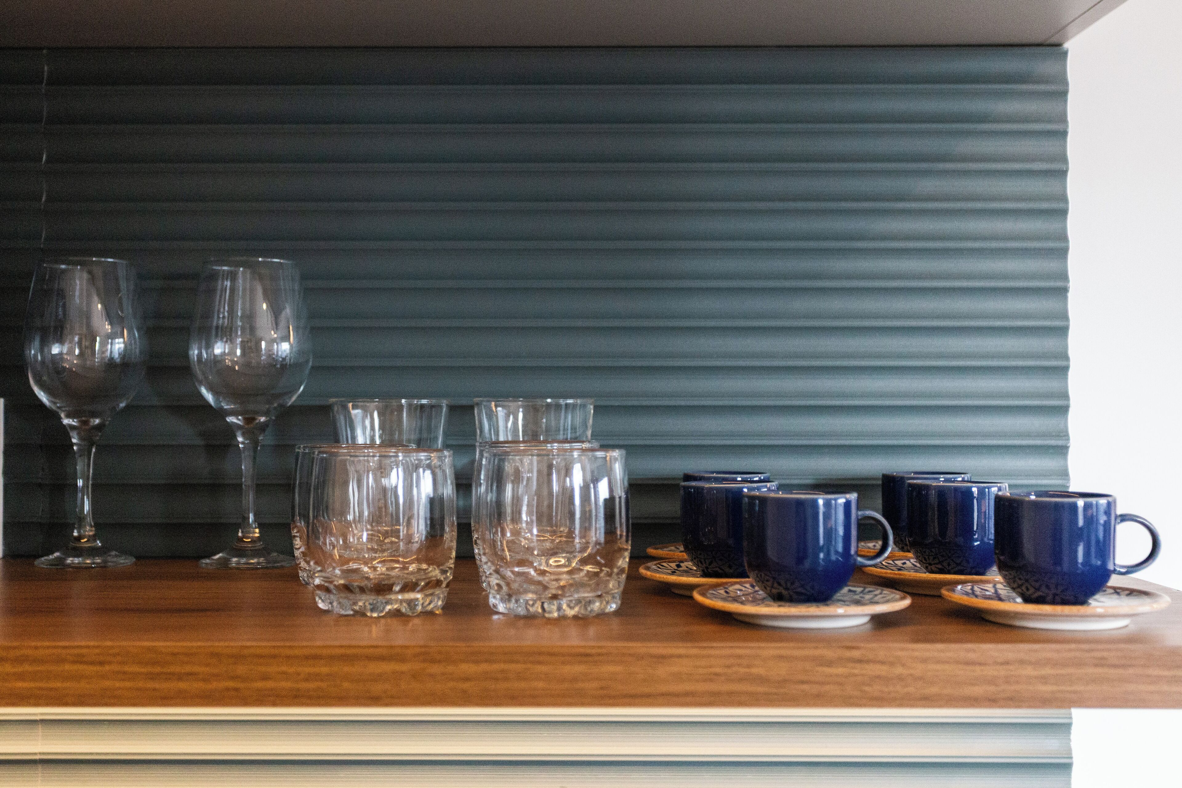 Een houten tafel met diverse glazen en blauwe keramische bekers.