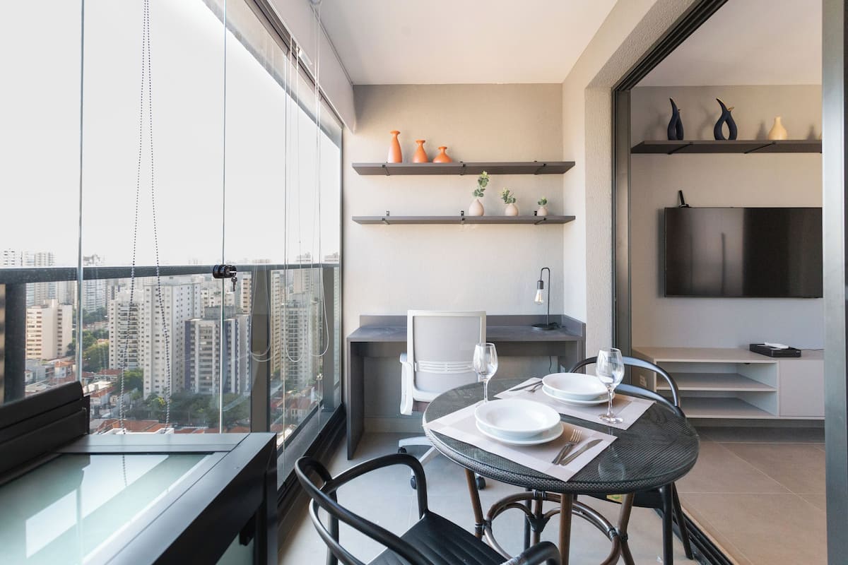 A modern apartment with a balcony, dining area, and TV.