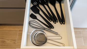 A drawer containing various kitchen utensils including spatulas, a whisk, and a strainer.