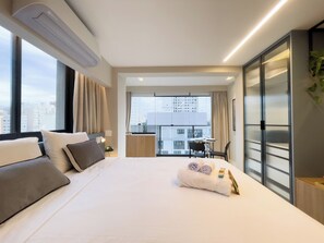 A modern hotel room with a large bed, a desk, and a view of the cityscape. - Go Platô Perdizes (Sao Paulo)