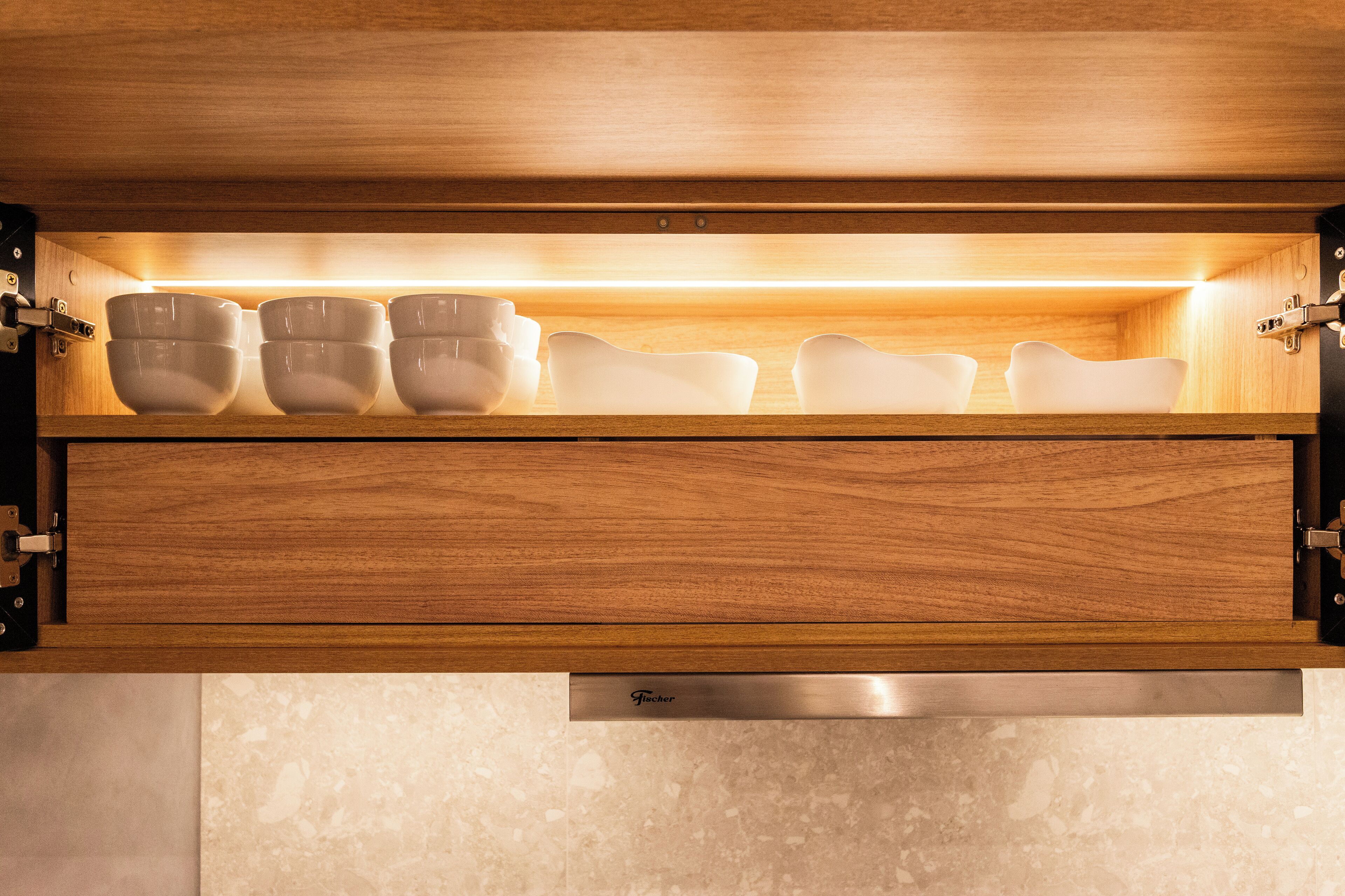 A kitchen cabinet with a built-in shelf holding white bowls.