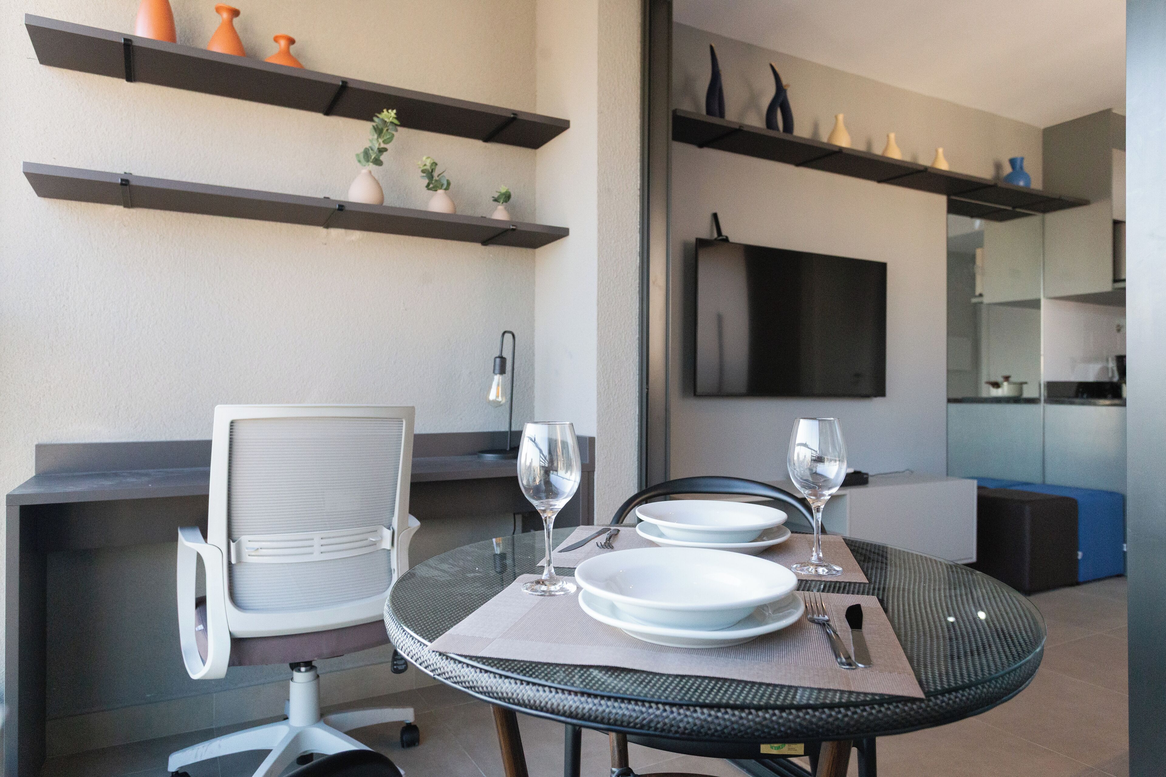 A dining area with a round table, chairs, and a TV mounted on the wall.