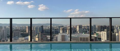 Una piscina al aire libre, sombrillas, sillones reclinables de piscina