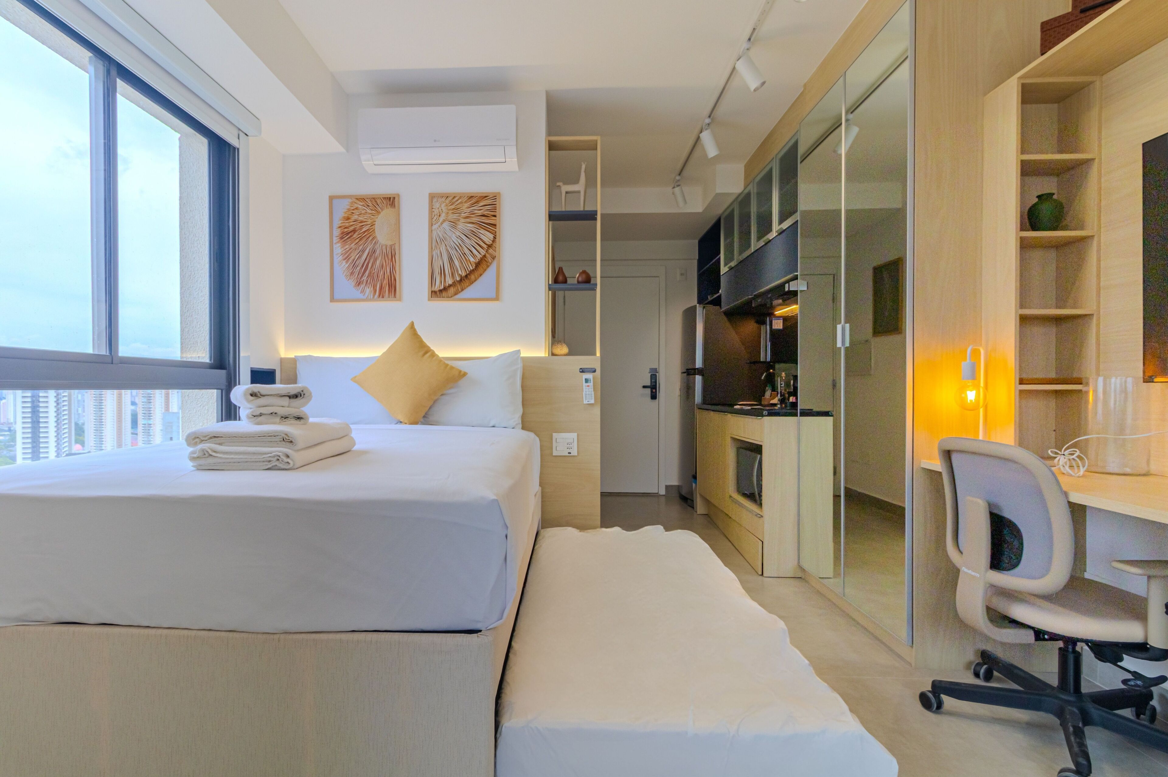 Una habitación de hotel moderna con una cama grande, un escritorio y una kitchenette.