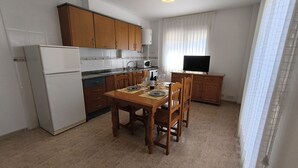 Una cocina compacta con armarios de madera, un refrigerador blanco y una mesa de comedor para dos.