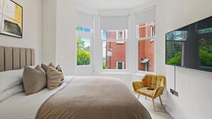 A bedroom with a large bed, a chair, and a TV.