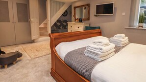 Une chambre à coucher avec un lit en bois, une télévision, un miroir, un escalier et une armoire.