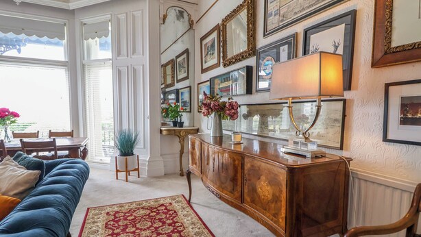 Un salon bien aménagé, avec un canapé bleu, un meuble en bois et un tapis rouge à motifs.