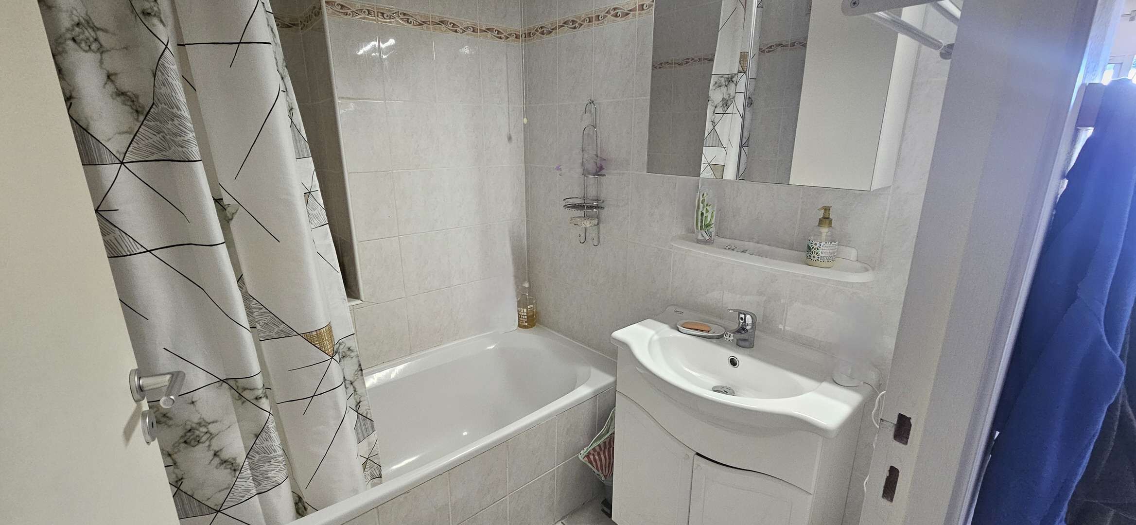 A bathroom with a bathtub, a sink, and a mirror.