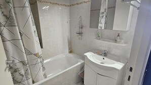 A bathroom with a bathtub, a sink, and a mirror.