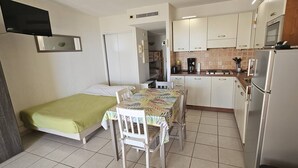 A compact room with a bed, a small dining table, and a kitchenette.