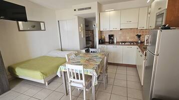 A compact room with a bed, a small dining table, and a kitchenette.