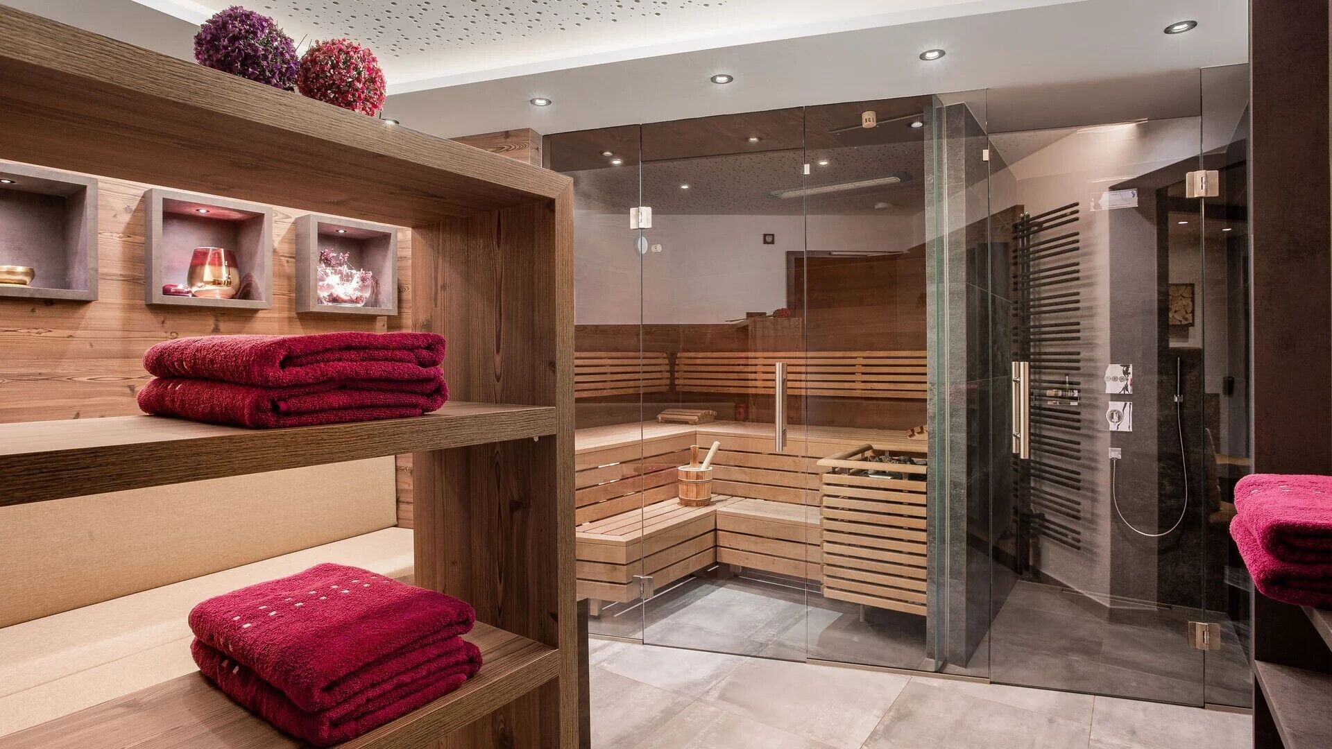 A modern spa with wooden shelves, a glass sauna, and a glass shower area.