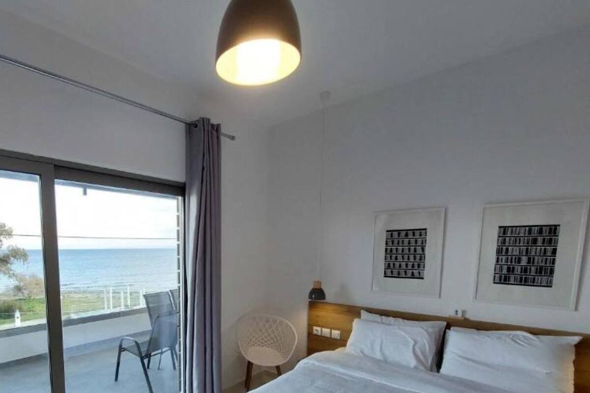 Une chambre avec une grande fenêtre, un lit, une chaise et un luminaire au plafond.