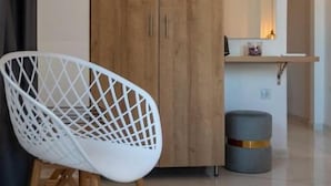 Una habitación moderna con un armario de madera, una silla blanca, una mesita redonda y un espejo sobre la mesa.