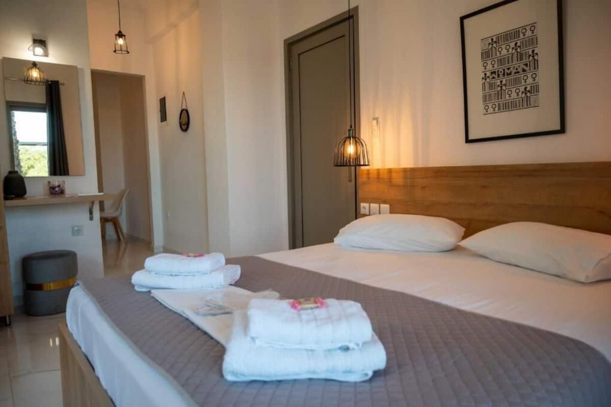 Une chambre d’hôtel comprenant un lit, une table de chevet, un miroir, une œuvre d’art accrochée au mur et une porte.