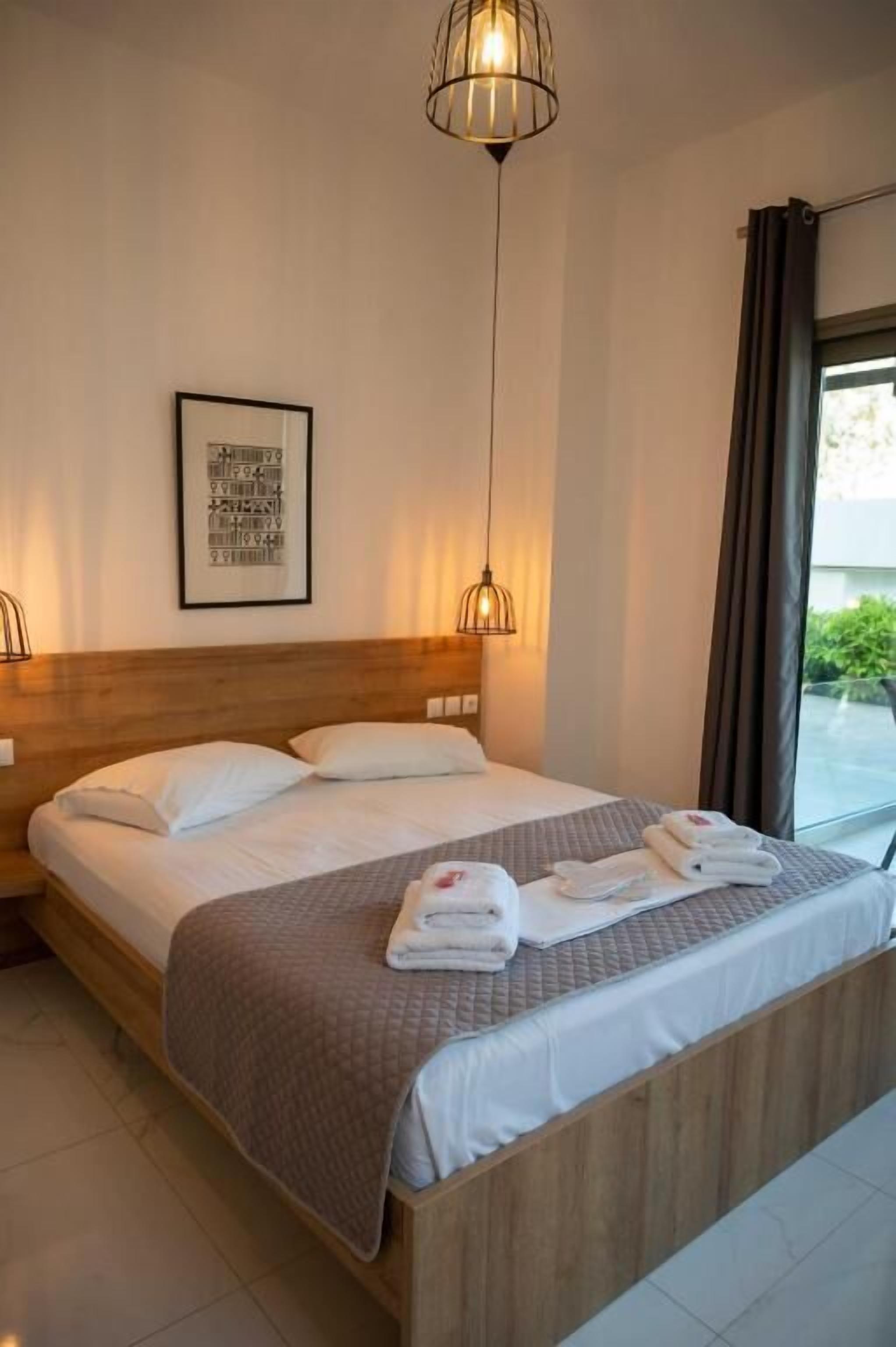 Una cama bien hecha con cabecera de madera, una mesita de noche y un cuadro enmarcado en la pared.