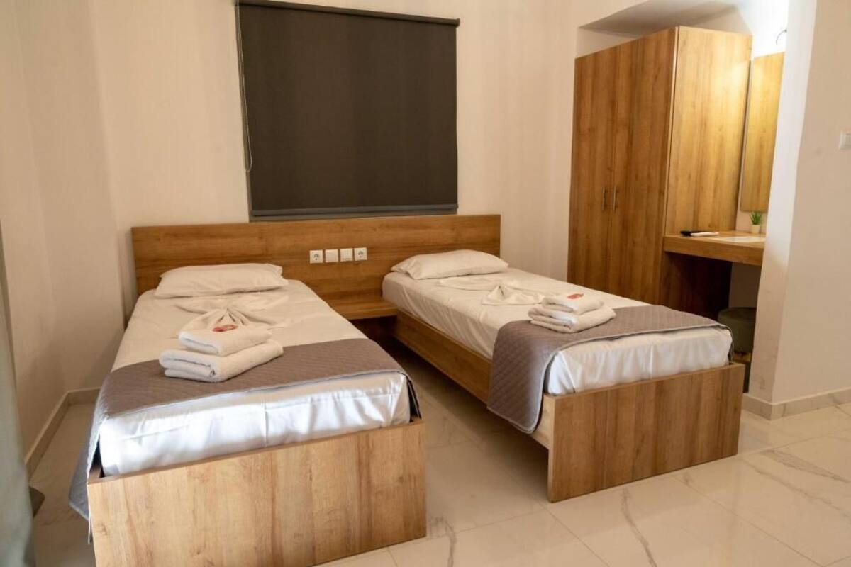 Une chambre d’hôtel avec deux lits en bois, une grande armoire et une petite table de chevet.
