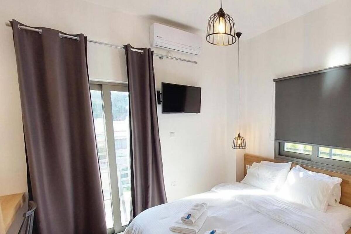 Une chambre d’hôtel équipée d’un lit, d’un téléviseur à écran plat, d’un système de climatisation et d’une fenêtre avec des rideaux.