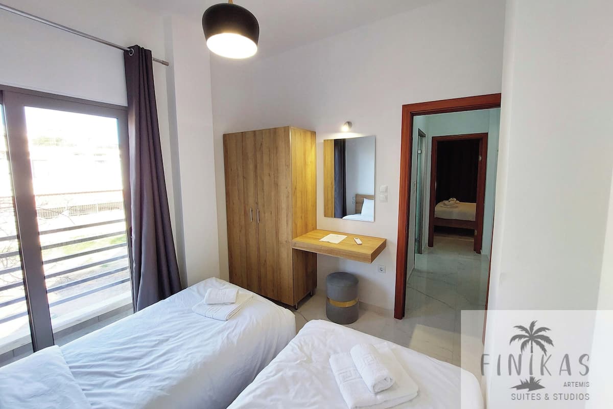 Une chambre d’hôtel avec deux lits, une armoire en bois, un petit lavabo et un miroir.