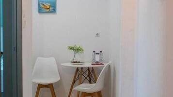 Un couloir étroit avec une petite table et deux chaises, une plante en pot et un tableau encadré au mur.