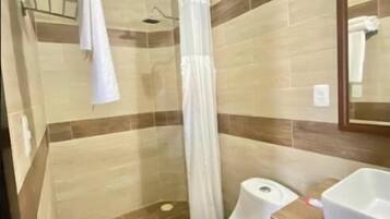 Une salle de bain avec douche, toilettes et lavabo.