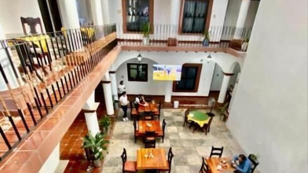 A spacious courtyard with multiple wooden tables and chairs, surrounded by white walls and a tiled floor. - HOTEL PINEDA REAL  (Tonalá)