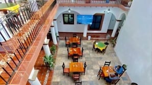 A spacious indoor area with multiple wooden tables and chairs, a tiled floor, and a balcony with railings. - HOTEL PINEDA REAL  (Tonalá)