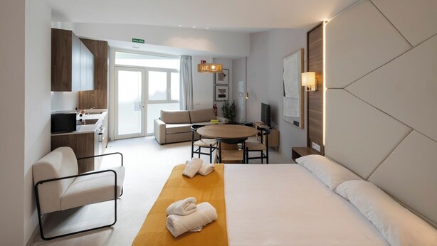 Une chambre d’hôtel comprenant un lit, un canapé, une table à manger, une télévision et une salle de bain avec douche.