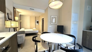 Une chambre d’hôtel moderne équipée d’un lit, d’un bureau, d’une chaise, d’une table ronde et d’un téléviseur.