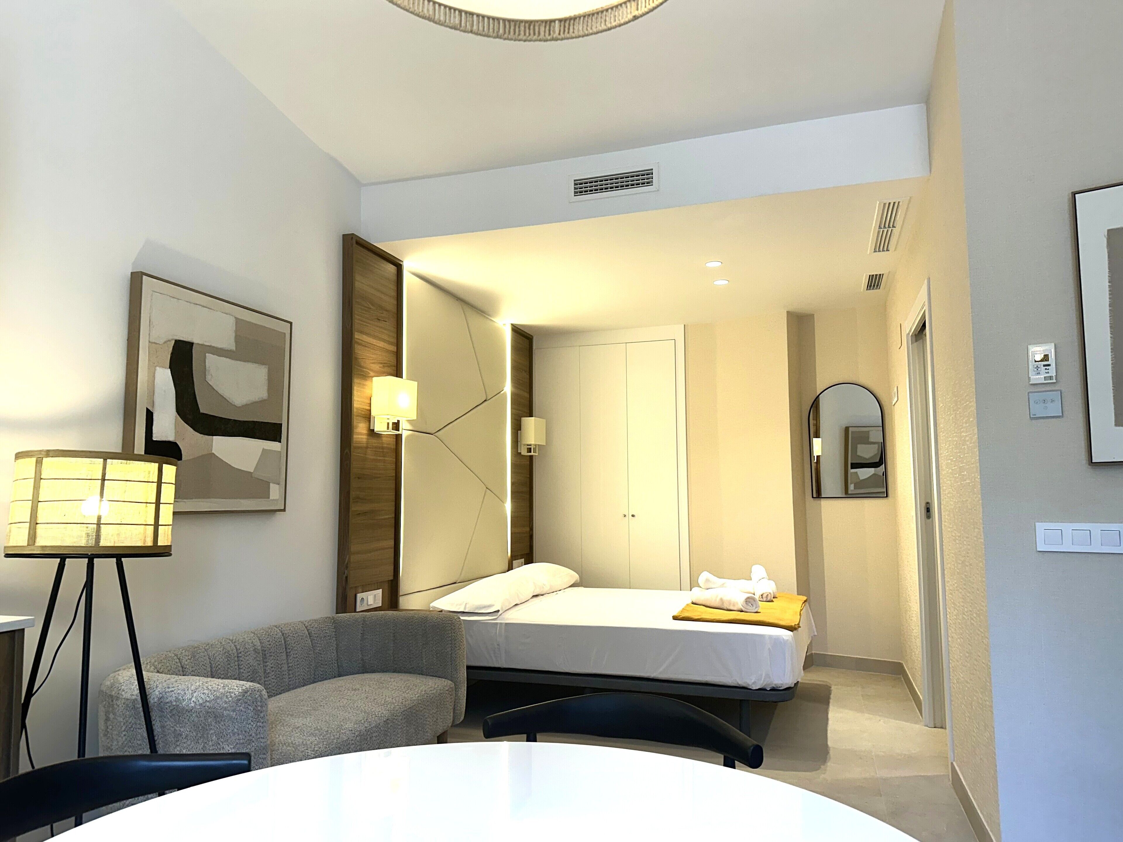 A hotel room with a bed, a sofa, a desk, and a lamp.