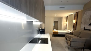 Une chambre d’hôtel moderne dotée d’une kitchenette élégante, d’un canapé confortable et d’un grand miroir.