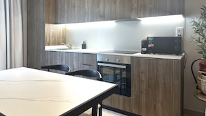 Une cuisine moderne avec des meubles en bois, un four encastré, un four à micro-ondes et une table à manger avec des chaises.