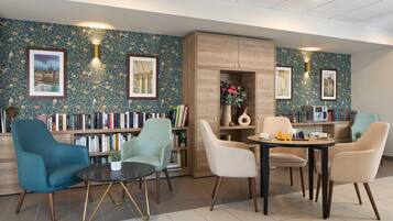 A modern lounge area with a bookshelf, seating, and a coffee table.