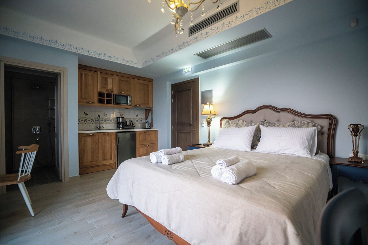 Un dormitorio con cama, mesita de noche, lámpara y silla de madera.
