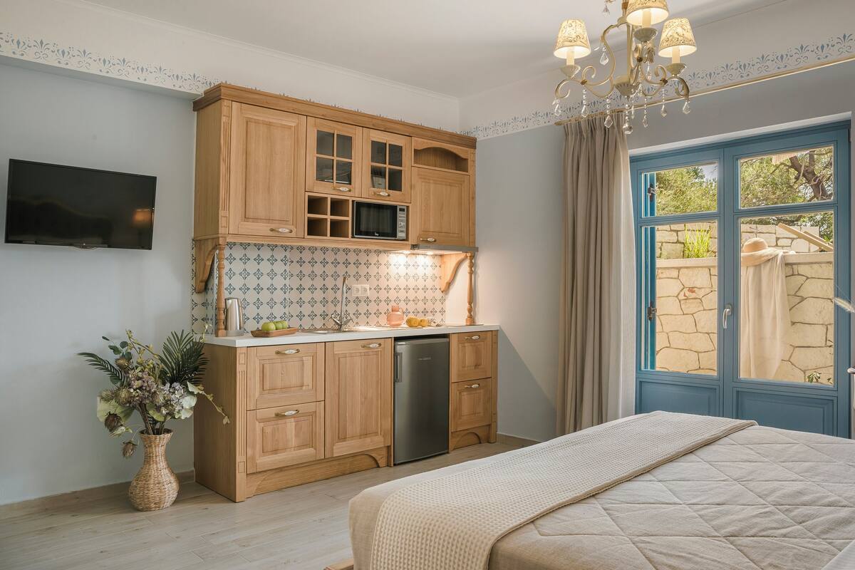 A bedroom with a bed, a wooden cabinet, a microwave, and a television.
