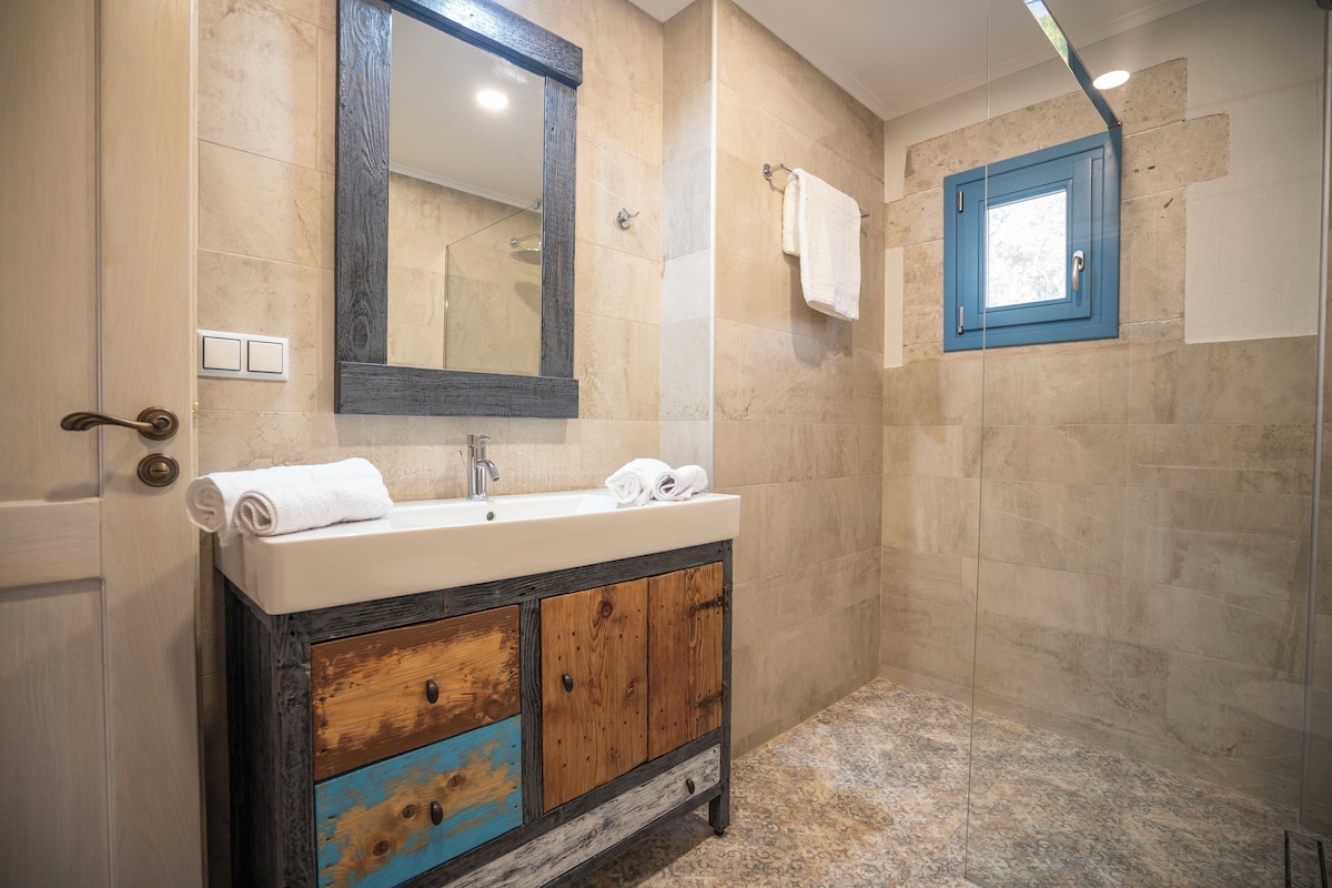 Un baño con lavamanos, espejo y ducha.